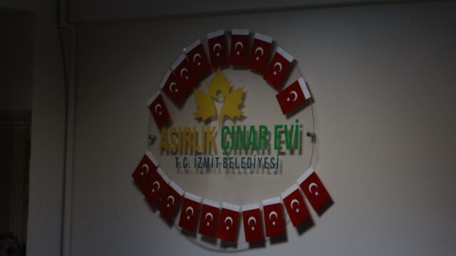 Duvarda Türk bayraklarıyla çevrili Asırlık Çınar Evi, T.C. İzmit Belediyesi yazılı tabela.