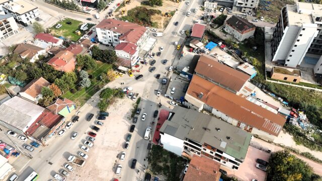 Havadan görünen yol, park halindeki araçlar ve çevredeki çatılı binalar