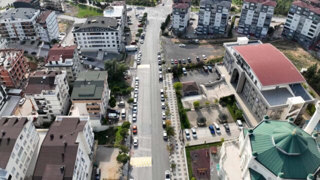 Havadan görünen, kenarlarında park etmiş araçlar bulunan cadde, yeşil kubbeli cami ve çevredeki apartmanlar.